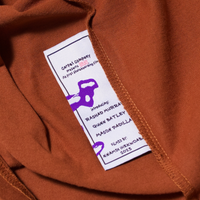 Brown tee's wash label with text describing the film BRAT