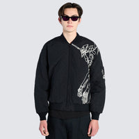 Male wearing black bomber jacket with cartoon imagery 