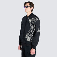 Male wearing black bomber jacket with cartoon imagery 